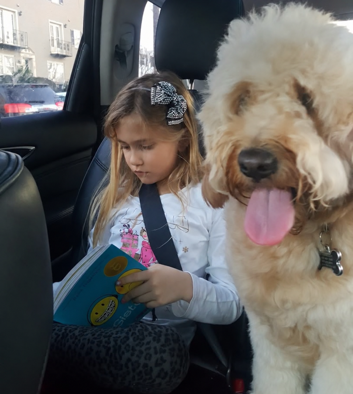 Young Cally looking at the pictures in a book beside the family dog